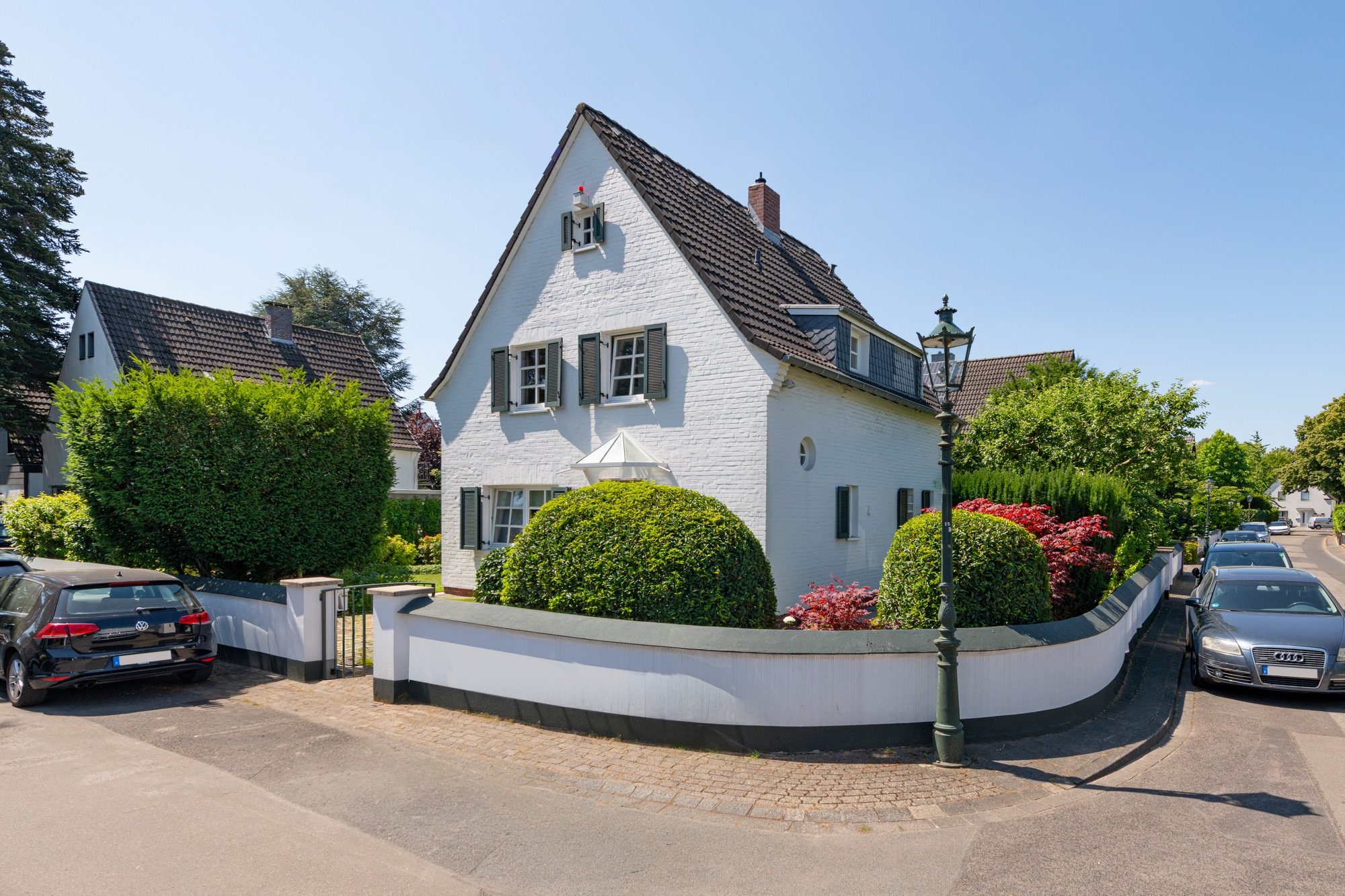 Foto eines freistehenden Einfamilienhauses umgeben con einer niedrigen Mauer. Beides in weiß gestrichen. Gepflegte Einfamilienhaus-Siedlung in düsseldorf-stockur Hausfoto